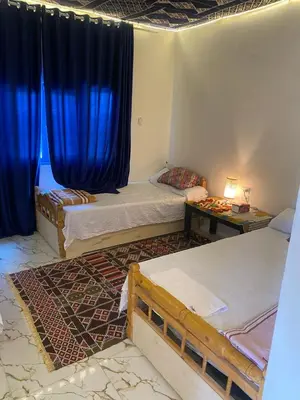 two beds in a room with blue curtains at hooly nubian in Aswan