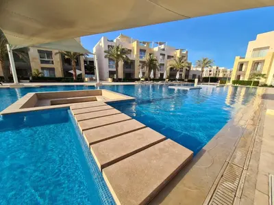 a swimming pool with blue water and some buildings at Mangarovy El Gouna in Hurghada