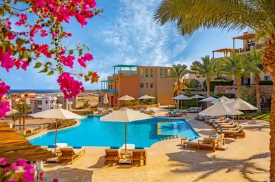 a resort with a swimming pool with chairs and umbrellas at AJIRA Resort Sahl Hasheesh in Hurghada