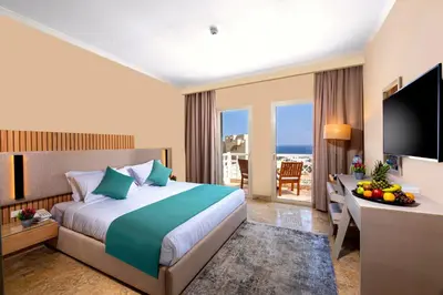 a hotel room with a bed and a desk with a television at AJIRA Resort Sahl Hasheesh in Hurghada