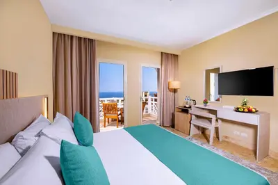 a hotel room with a bed and a desk with a television at AJIRA Resort Sahl Hasheesh in Hurghada