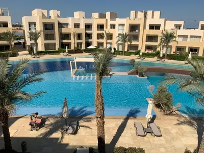 a large swimming pool with palm trees in front of a building at Elgouna Hurghada egypt mangroovy in Hurghada