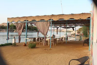 a table and chairs under a pavilion next to the water at Nile View Guest House in Aswan