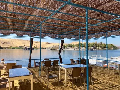 a patio with tables and chairs and a view of a river at Nile View Guest House in Aswan