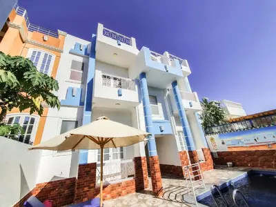 a blue and white building with an umbrella at Sunshine House in Luxor