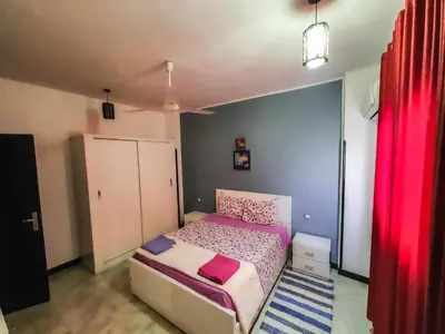 a small bedroom with a bed and a red curtain at Sunshine House in Luxor