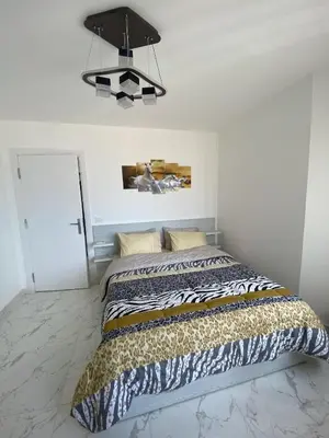 a bed in a white room with a chandelier at Blue Whale Hurghada Beach Front Apartments City Centre in Hurghada