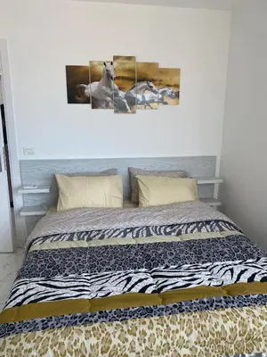 a bed in a bedroom with two paintings on the wall at Blue Whale Hurghada Beach Front Apartments City Centre in Hurghada