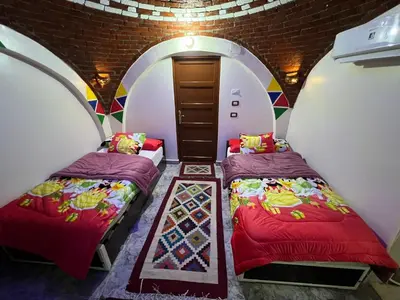 two beds in a room with a brick wall at Noura hasel nubian house in Aswan
