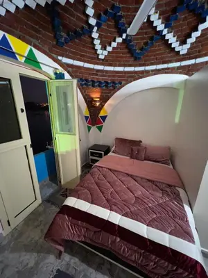 a bedroom with a bed and a brick wall at Noura hasel nubian house in Aswan