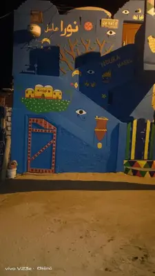 a bedroom with a blue wall with a train on it at Noura hasel nubian house in Aswan