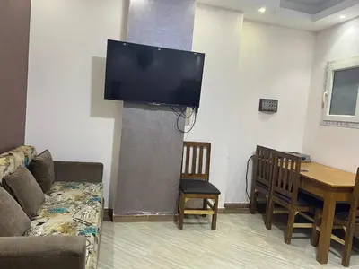 a living room with a couch and a tv on the wall at Compound cecelia in Hurghada
