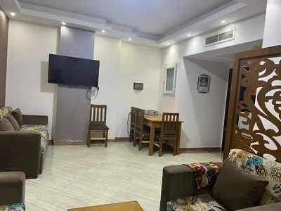 a living room with a tv and a table and chairs at Compound cecelia in Hurghada