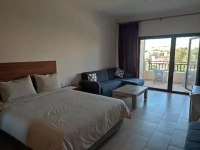 a bedroom with a bed and a living room with a couch at Aldau Heights Cozy big studio in Hurghada