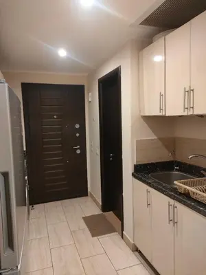 a kitchen with white cabinets and a black door at Aldau Heights Cozy big studio in Hurghada
