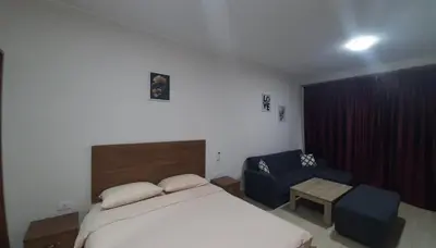 a bedroom with a bed and a blue chair at Aldau Heights Cozy big studio in Hurghada