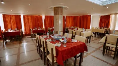 a dining room with tables and chairs and red curtains at New Sunset Resort in Aswan