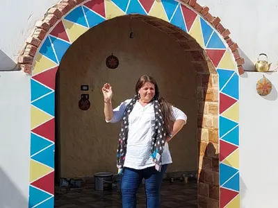 a woman standing in front of a colorful archway at Mostafa Nubian Guesthouse in Najâ€˜ al MadÄbb