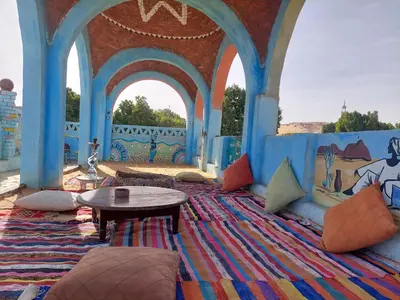 a room with a table and chairs on a rug at Mostafa Nubian Guesthouse in Najâ€˜ al MadÄbb