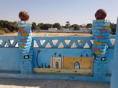 a painting of a house on a blue wall at Mostafa Nubian Guesthouse in Najâ€˜ al MadÄbb