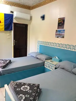a room with two beds with a door and a door at Cattleya Guesthouse in Aswan