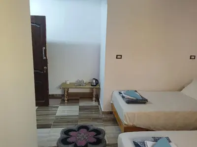 a small room with two beds and a table at Cattleya Guesthouse in Aswan