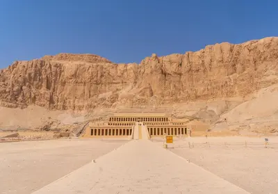 a building in the desert with a mountain in the background at Mikhaila Guest House in Luxor