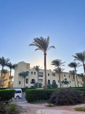 a building with palm trees in front of it at Snorkeling Paradise 5 Star Resort Stella Makadi in Hurghada
