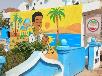 a mural of a man playing a flute on a wall at Nubian Wessy Ka Guest House in Aswan