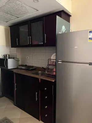 a kitchen with a stainless steel refrigerator and wooden cabinets at Cecelia resort in Hurghada