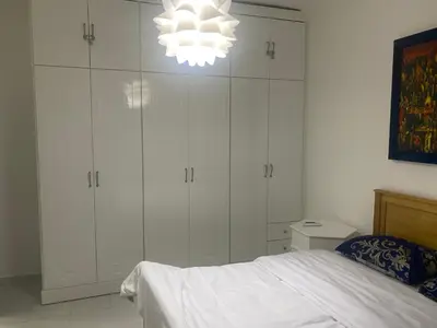 a bedroom with white cabinets and a bed and a chandelier at One Bedroom with Balcony WI-FI Downtown Sheraton Plaza 226 in Hurghada