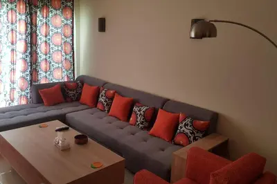 a living room with a blue couch with red pillows at Sahl Hasheesh Deluxe penthouse Veranda in Sahl Hasheesh