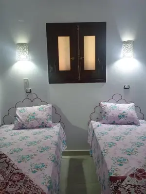 a bedroom with two beds and two lights on the wall at Nubian Queen Guest House in Aswan
