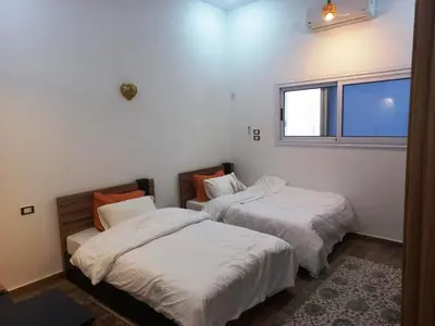 two beds in a room with a window at Twilight palace in Luxor