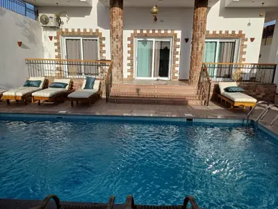 a large swimming pool with benches at Twilight palace in Luxor