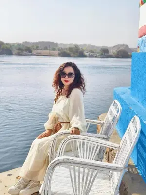 a woman sitting on a chair next to the water at DoroKa Nubian House in Aswan