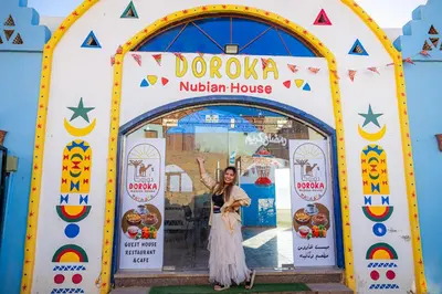 a woman standing in front of a door to a kitchen house at DoroKa Nubian House in Aswan