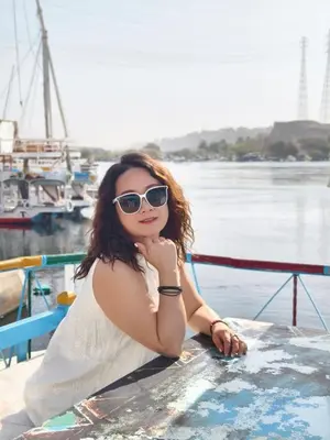 a woman in sunglasses is sitting on a boat at DoroKa Nubian House in Aswan