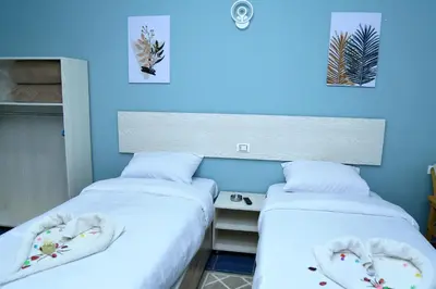 two beds sitting next to a desk in a room at Lamera Hotel in Hurghada
