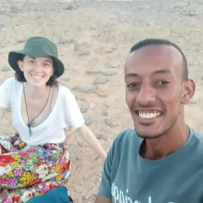 a man and a girl sitting on the beach at Zekry nubian guest house in Aswan