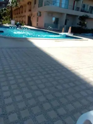 a swimming pool with a tile floor in front of a building at كذا بلانكا بيتش 220 in Hurghada