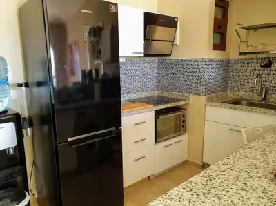 a kitchen with a black refrigerator and white cabinets at Brand New Waterfront Sabina Ground Floor Home in Hurghada