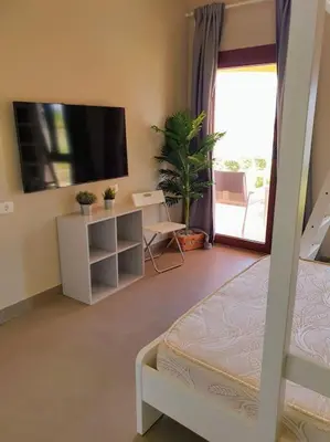 a bedroom with a bed and a tv and a balcony at Brand New Waterfront Sabina Ground Floor Home in Hurghada