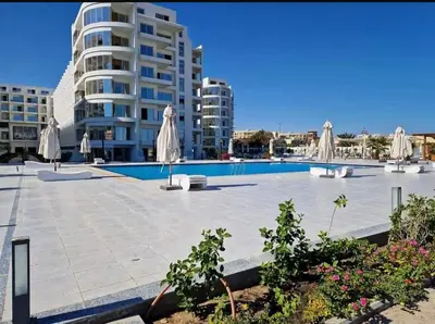 a swimming pool with umbrellas and a building at شقة داخل كمباوند in Hurghada