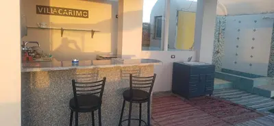a kitchen with two bar stools and a counter with a sink at Sunny sky in Quseir