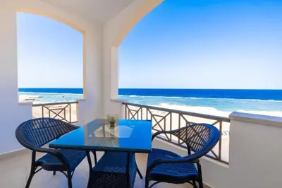 a table and chairs on a balcony with the ocean at Oyster Bay Beach Suites in Abu Dabab
