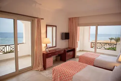 a hotel room with a bedroom with a view of the ocean at Oyster Bay Beach Suites in Abu Dabab