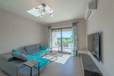 a living room with a blue couch and a table at Bright 2-Bedroom Apartment with Golf Course & Pool View l Cyan, El Gouna in Hurghada