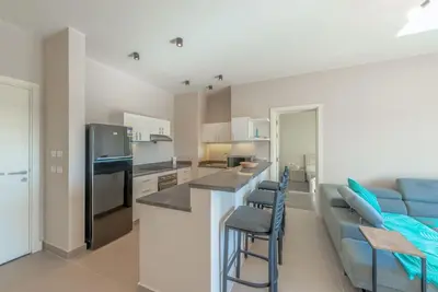 a kitchen and living room with a couch and a counter at Bright 2-Bedroom Apartment with Golf Course & Pool View l Cyan, El Gouna in Hurghada