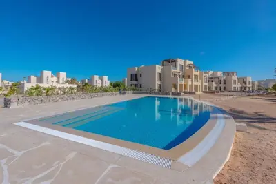 a swimming pool in a resort with buildings in the background at Bright 2-Bedroom Apartment with Golf Course & Pool View l Cyan, El Gouna in Hurghada